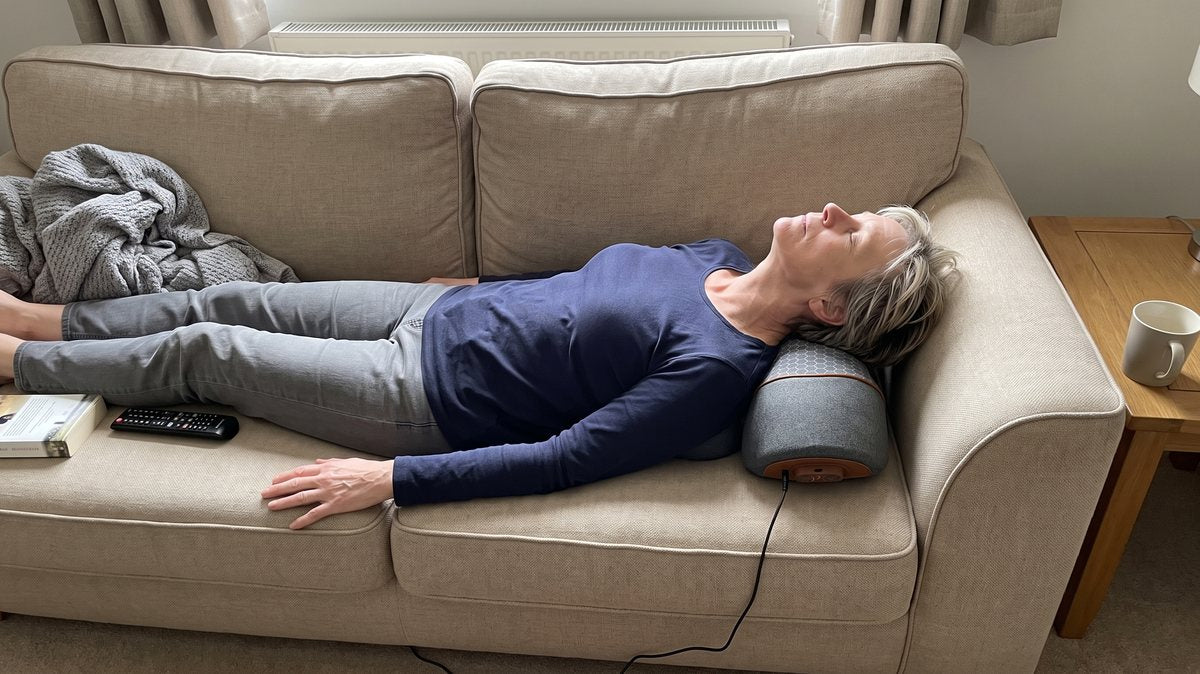 Lying back along her daughter's sofa with the FisioRest under her neck, her chin lifted and her head tipped further back than she expected, eyes closed.
