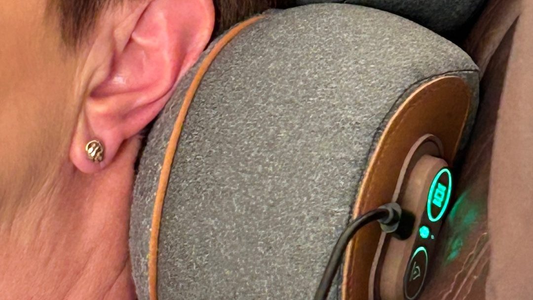 A customer photograph, close in, of the FisioRest under the back of a neck with the controls lit.