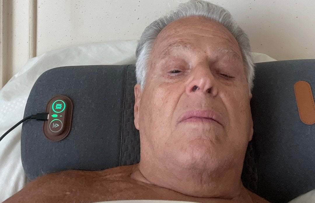 A customer photograph of a man lying back with his head tipped over the FisioRest, eyes closed.