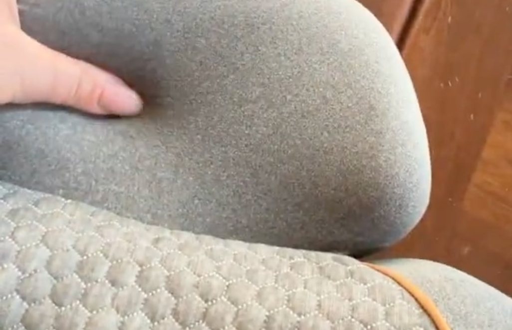 A customer photograph, close in, of the two padded lobes of the FisioRest that sit either side of the base of the neck, with a hand resting on one.